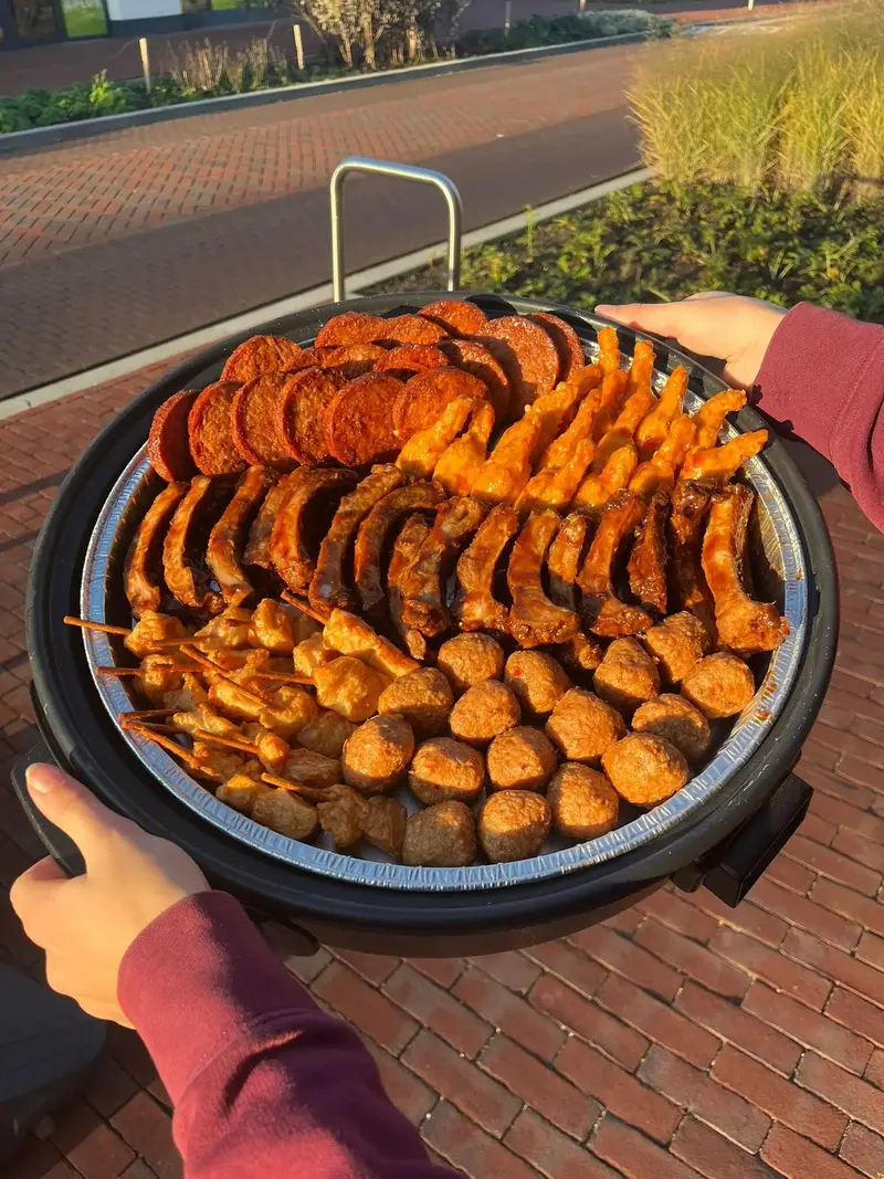 Hapjespan met spareribs en warme hapjes, vastgehouden boven een stoeptegelpad