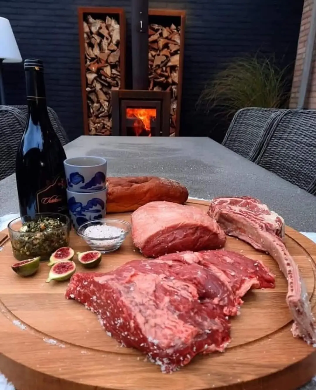 Houten snijplank met vers rundvlees, een fles wijn en een haard op de achtergrond